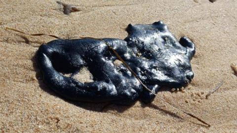 Black bitumen debris which has washed up on an Essex beach.