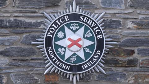 The Police Service of Northern Ireland badge pictured against a stone wall. 