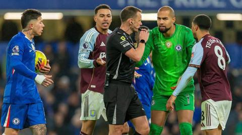 Chelsea's Enzo Fernandez and Robert Sanchez arguing with the match referee, along with Villa's Youri Tielemans and Morgan Rogers
