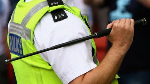 A police officer holding an extendable baton