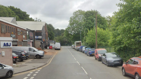 A google street view imagine of a road on an industrial estate with cars parked on the right hand side kerb