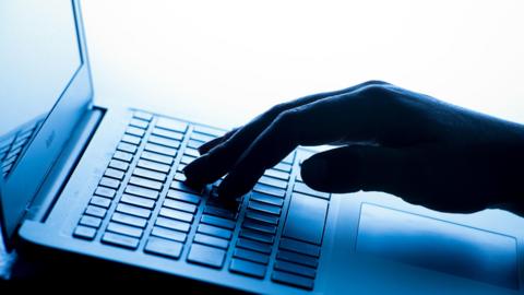 A hand on a keyboard in a blue shade of light.