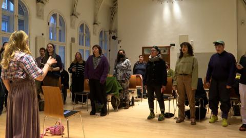 A' Chòisir Chuèir a' seinn san talla.