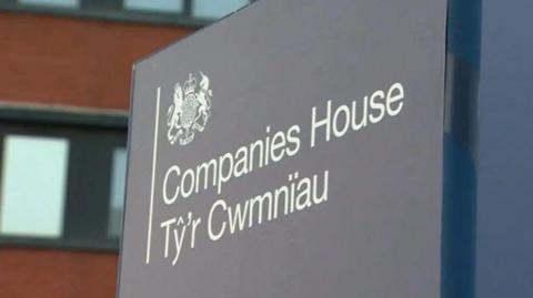 A sign with 'Companies House' and its translation in Welsh written on it. The sign is grey with the writing in white.