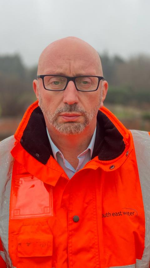 A bald man wearing glasses and a hi-vis jacket