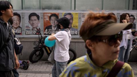 People walk past electoral posters of South Korea's presidential candidates in Seoul, South Korea.
