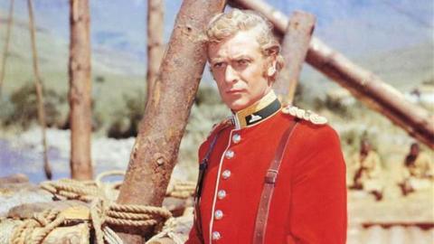 Sir Michael Caine, wearing a red British Army uniform in a publicity portrait issued for the 1964 war film Zulu. The historical drama depicted the Battle of Rorke's Drift in South Africa, during the Anglo-Zulu War. Caine starred as Lieutenant Gonville Bromhead.