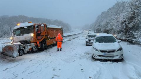 Cars stopped on a motorway with snow covering them and the ground