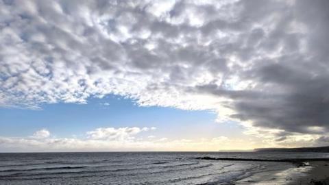 A chink of blue sky with grey clouds rolling in over the coast 