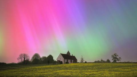 An isolated building in the foreground with a colourful Northern Lights display in the background