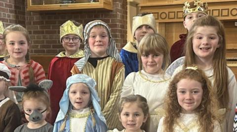 A group of primary school children dressed up in nativity costumes.