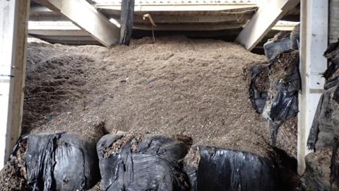 Brown waste piled to the ceiling in an industrial unit