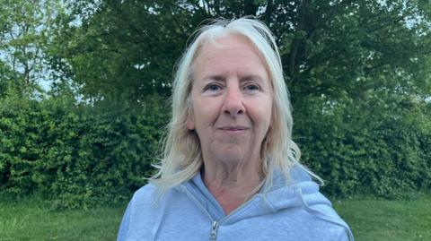 A woman with blonde hair wearing a grey hoodie top