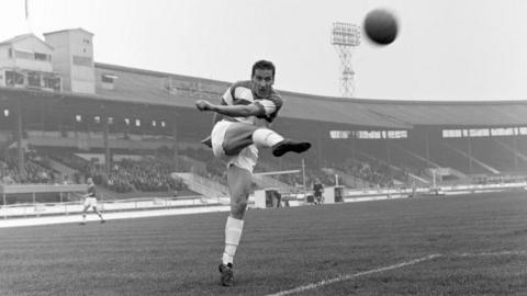 A black and white picture of Mark Lazarus taking a shot.
