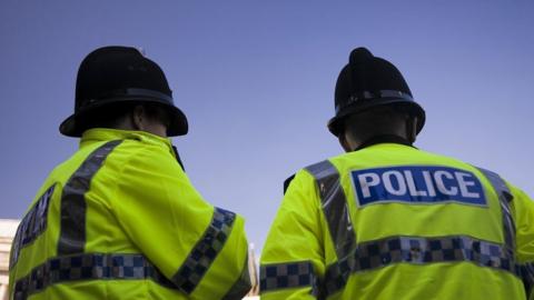 Two police officers wearing high-vis jackets and black helmets