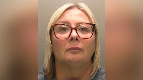 Police photograph of a bespectacled woman with fair hair. She is looking directly at the camera.