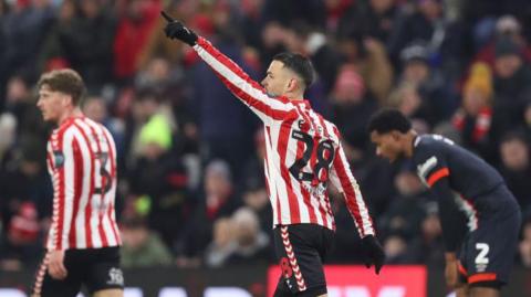 Enzo Le Fee with his hand aloft in celebration, pointing towards someone in the crowd, after his goal against Luton