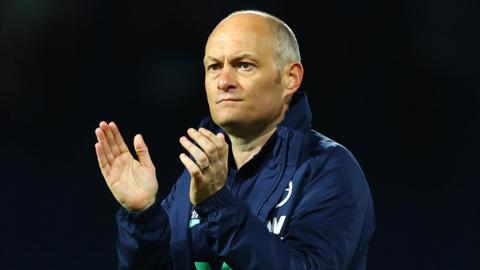 Alex Neil, wearing a navy blue Millwall jacket with the club badge on the chest, claps his hands to the travelling fans after the 0-0 draw at West Brom