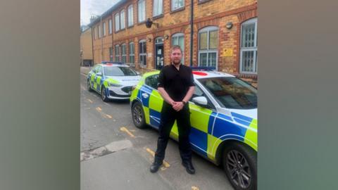 A police officer stands in front of police cars