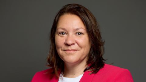 Anna Turley's official portrait. She has mid-length brown hair and is looking at the camera with a neutral expression. She is wearing a white shirt and pink blazer.