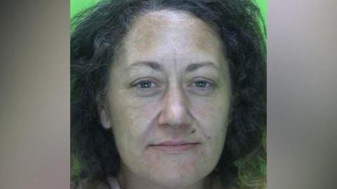 Mugshot of Sally Knowles, who has dark hair and a piercing above her lip.