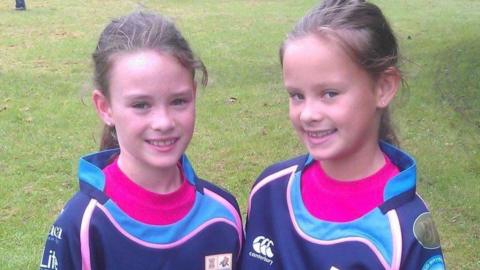 An old image showing Ffion and Celyn standing on a field smiling at camera in rugby kit.
