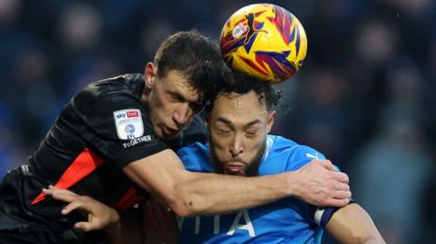 Birmingham City's Krystian Bielik and Stockport County's Kyle Wootton challenge for the ball