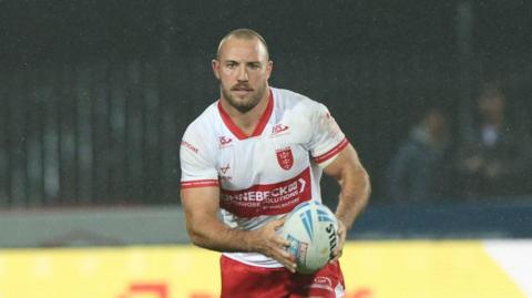 Karl Lawton carrying the ball in both hands but slightly towards his left-hand side playing for Hull KR