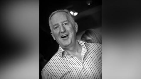 Nick is wearing a shirt with vertical stripes in a black and white photo