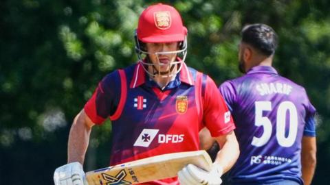 Zak Tribe holding a cricket bat during a game.