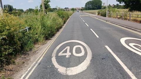 The road known locally as "the causeway" with a 40 miles per hour symbol on the road and a pavement on one side of the road