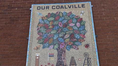A large colorful mosaic of a tree with words that read "Our Coalville"