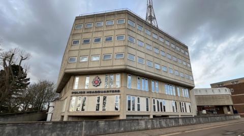 Essex Police's headquarters in Chelmsford. It is a large concrete building of several storeys and is quite dull in its appearance. It fronts on to a road.
