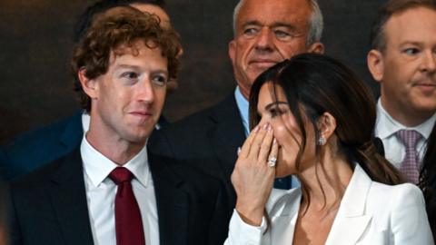 Lauren Sanchez whispering to Mark Zuckerberg, who is smiling - Zuckerberg is wearing a suit, and Ms Sanchez has a white blouse on 