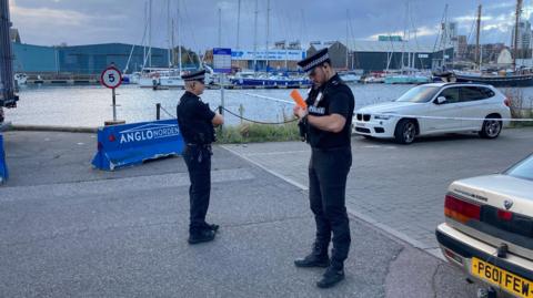 Two uniformed police officers stand at Ipswich Marina.