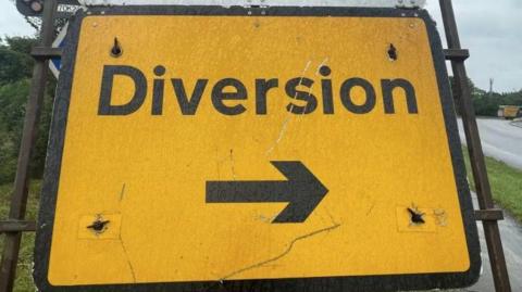 A large yellow sign has a black arrow pointing right and black text that says Diversion.