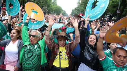 Crowds of people raise their hands up in an attempt to break the Guinness World Record for the world’s largest Mexican wave