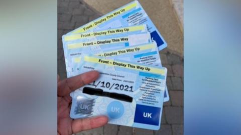 A hand holds on to five blue badges which have been confiscated. 