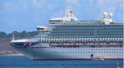 The cruise liner Ventura. It is a large white vessel with red and white branding moored on blue water