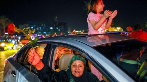 Woman and child celebrate in Damascus while driving in a car on 13 May