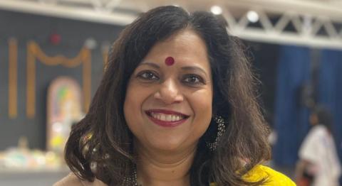 Barnali Ghosh smiling at the camera, in the background is a decorated stage.