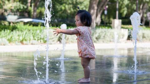 Baby playing with a water fountain
