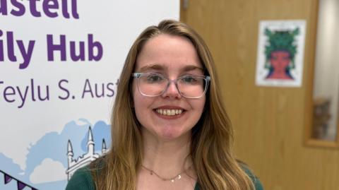 Charlotte Allen-Squire has long light brown hair down past her shoulders and wears glasses and a dark black top.