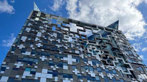 Looking up to the Cube building, which features a mix of glass and plus shaped panels