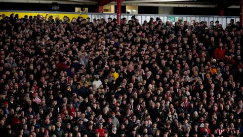 Exeter City fans during the Emirates FA Cup fourth round match at St James Park, Exeter. Almost the entire image is made up of hundreds of fans stood in the stands at the ground