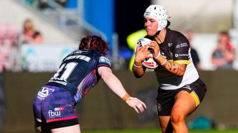 Rhiannion Marshall about to be tackled by Wigan Warriors' Eva Hunter