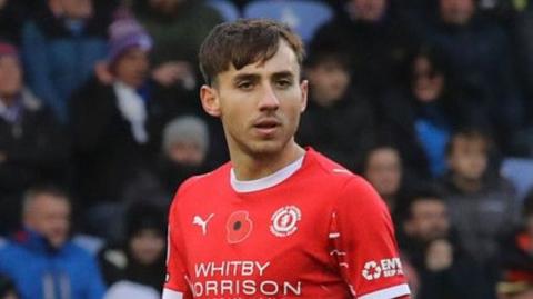 Crewe midfielder Matúš Holíček head shot wearing home red and white kit and looking ahead