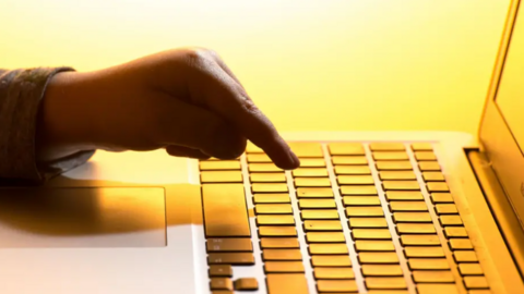 Generic yellow-lit image of a hand poised over a keyboard