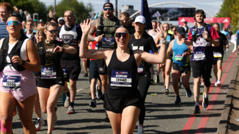 Runners in a large group, all with numbers pinned to their vests.