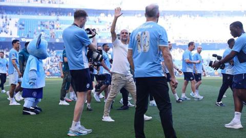 Manchester City manager Pep Guardiola is surrounded as he waves farewell.